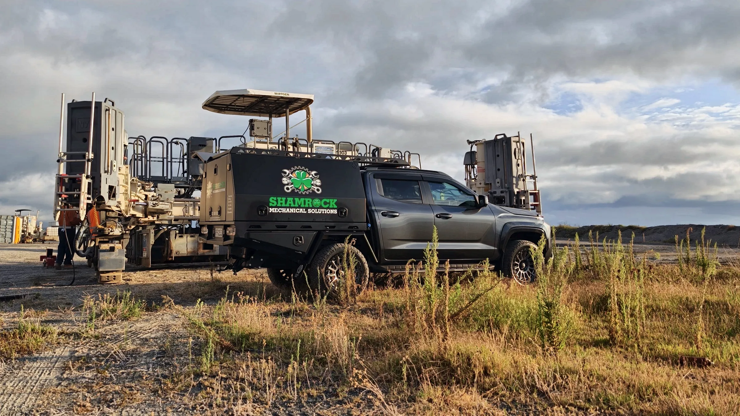 Shamrock service truck parked beside a drilling rig on a grass site