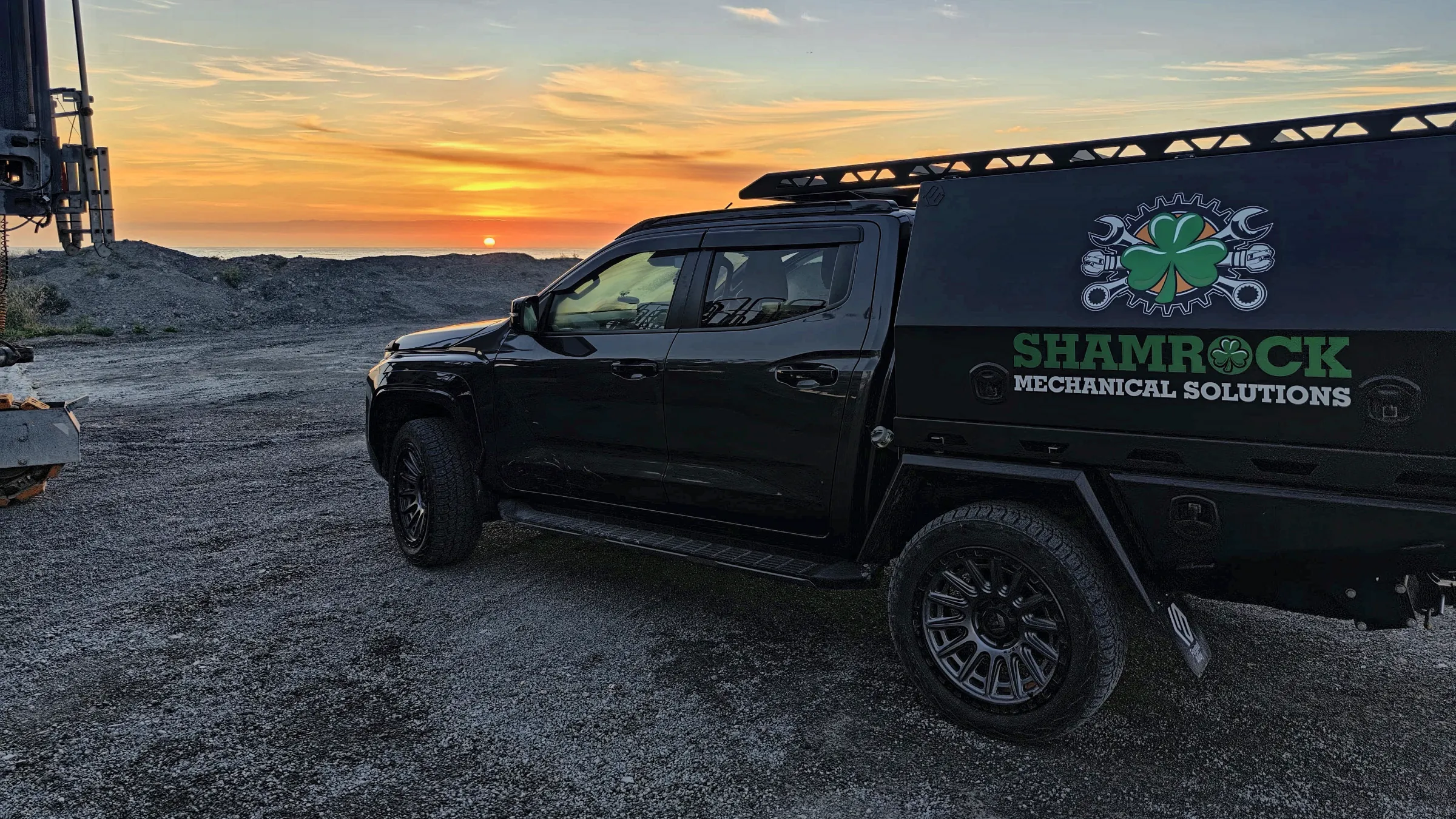 Shamrock service truck at sunset next to a drilling rig